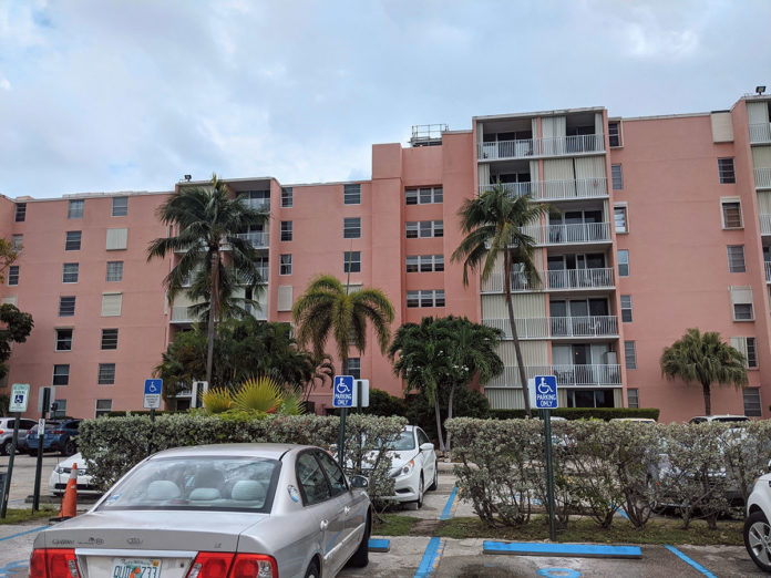 a parking lot with cars parked in front of a pink building