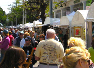 a crowd of people walking down a street next to tents