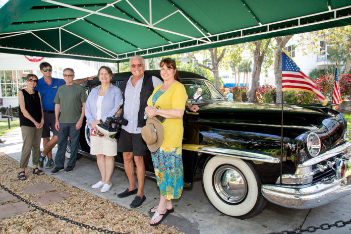 a group of people standing in front of a classic car