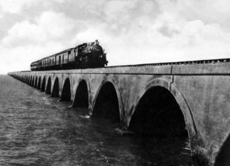 a black and white photo of a train on a bridge