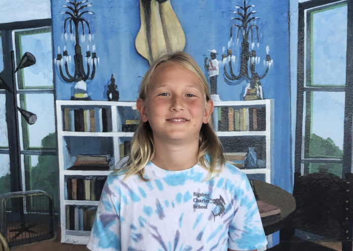 a young girl standing in front of a painting of a guitar
