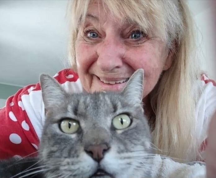 a woman holding a cat with a smile on her face