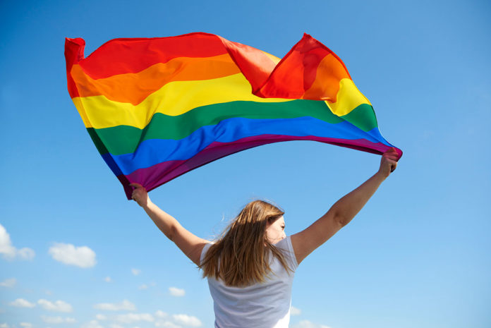 woman-waving-rainbow-flag a woman holding a rainbow flag in the air