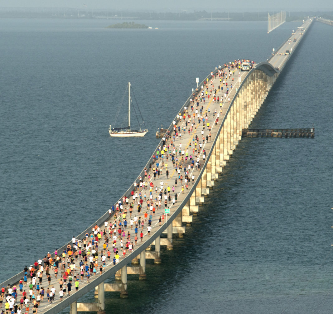 a large group of people walking across a bridge over water