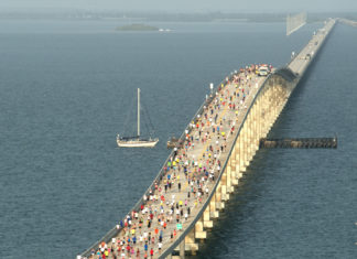 a large group of people walking across a bridge over water