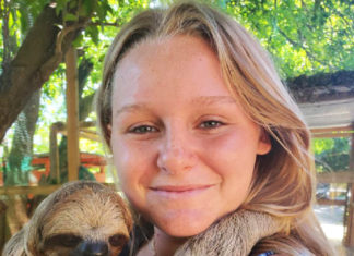 a woman holding a baby sloth in her arms
