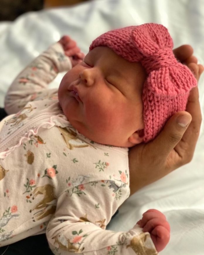 a woman holding a baby wearing a pink hat