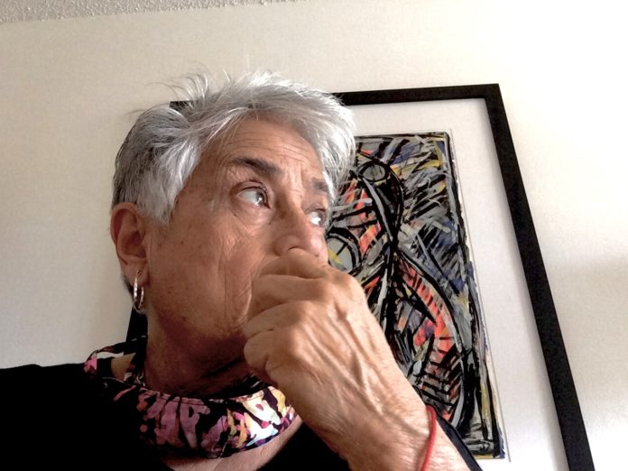 Blanqui Ga՛lvez an older woman is looking up in front of a painting