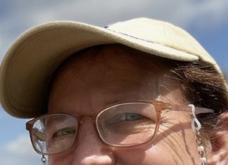 a woman wearing glasses and a hat standing next to a man