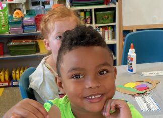 a boy sitting at a table with a cut out of paper