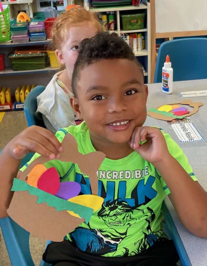a boy sitting at a table with a cut out of paper
