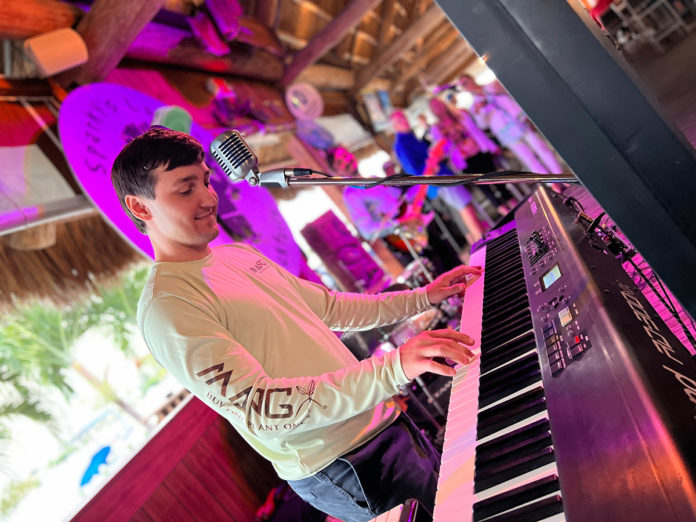 a young man is playing the piano in a bar