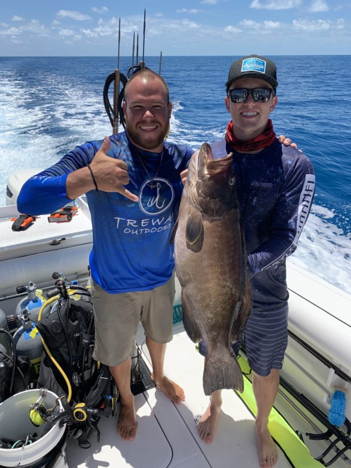 two men on a boat holding a fish