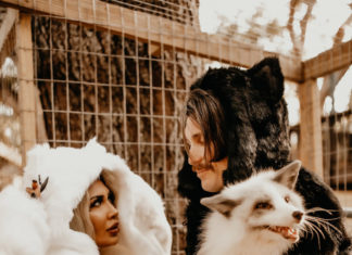a woman in a fur coat standing next to a cat