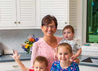 a woman and two children standing in front of a pan of cookies