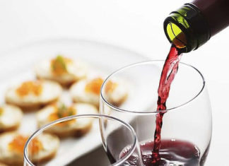 a glass of red wine being poured into a wine glass