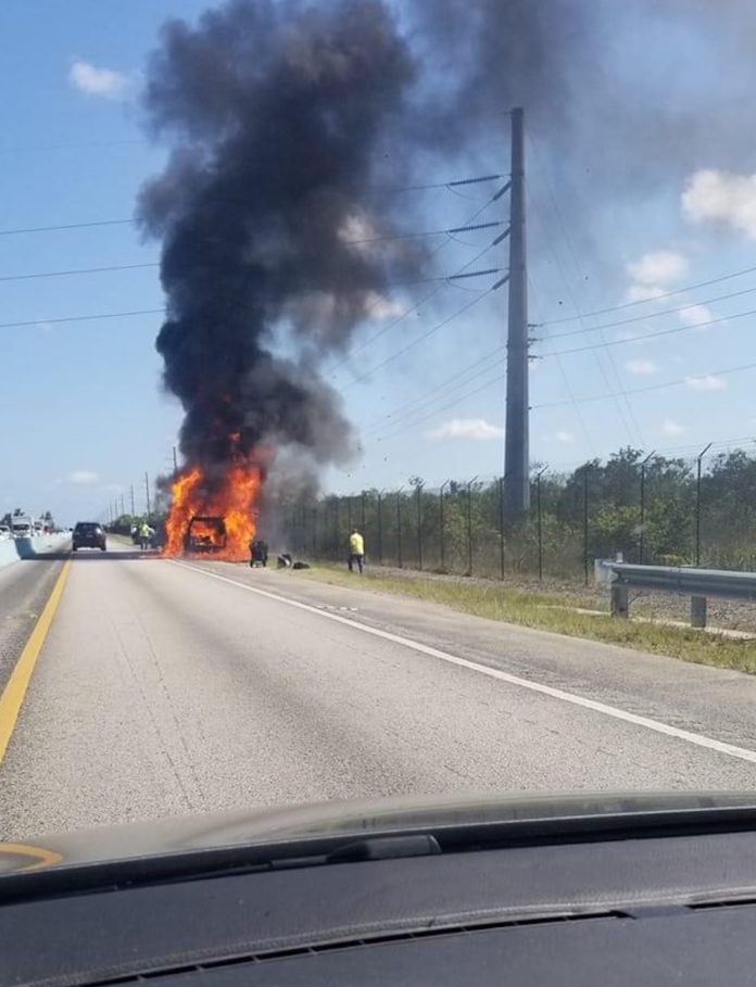 a car on fire on the side of the road