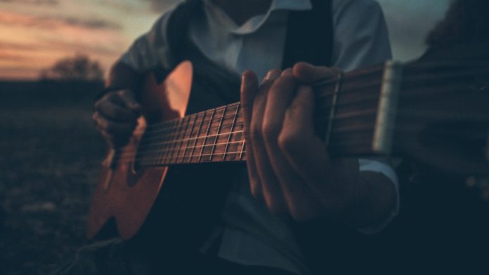 a man playing a guitar in a field