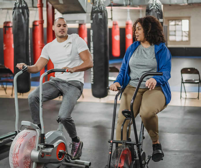 a man and a woman on exercise bikes in a gym