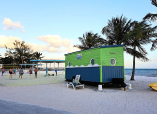 a small green and blue building on the beach