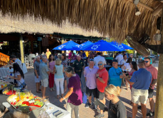 a group of people standing around a table with food on it