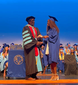 a graduate shakes hands with a woman in a gown