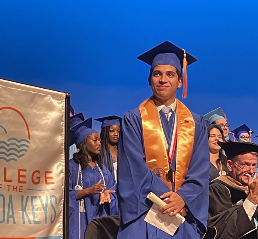 a man in a graduation cap and gown standing in front of a group of graduates