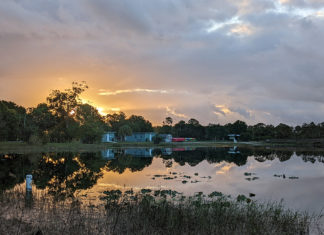 the sun is setting over a small lake