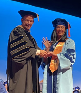 a man and woman shaking hands at a graduation ceremony