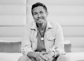 a black and white photo of a man sitting on a bed