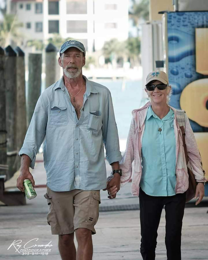 a man and woman walking down a sidewalk holding hands