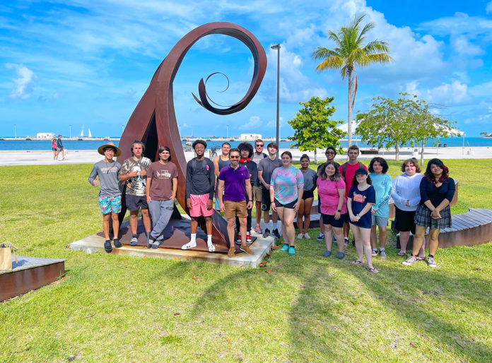 students-with-sculptor a group of people standing in front of a sculpture