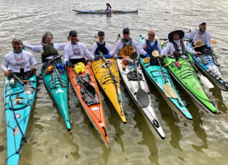 a group of men standing next to each other in kayaks