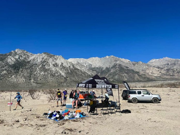 a group of people standing around a tent in the desert