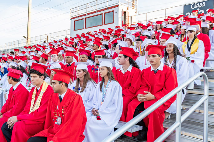 a large group of people in red and white graduation gowns