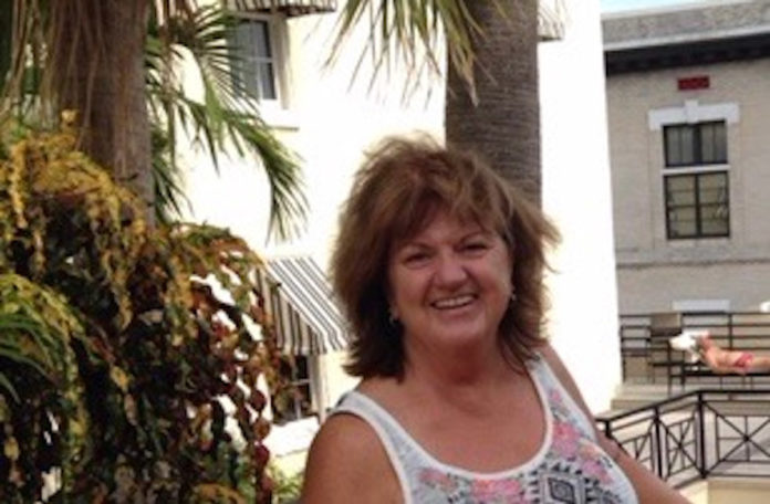 a woman standing next to a palm tree