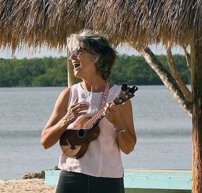 a woman playing a guitar under a straw hut