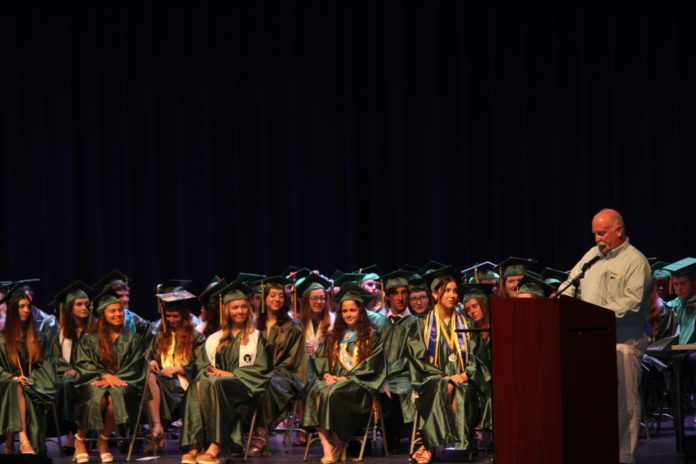 a man standing at a podium in front of a group of graduates