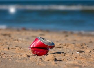 a red can sitting on top of a sandy beach