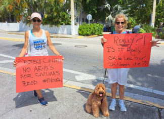 a couple of women standing next to each other holding signs