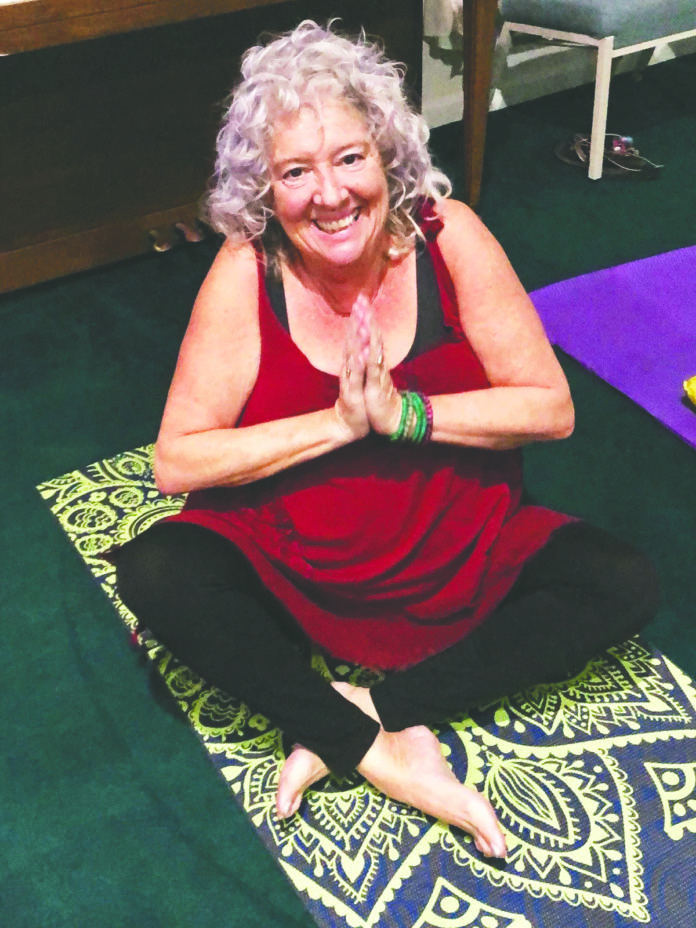 a woman sitting on a yoga mat in a room