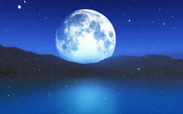 a full moon rising over a body of water