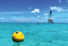 a yellow buoy floating in the ocean next to a light house