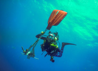 a man in a scuba suit is holding a kayak in the water