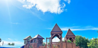 a playground with a wooden structure and a green slide