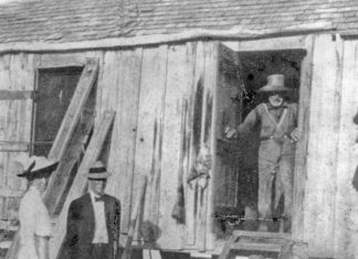 a group of people standing outside of a wooden building