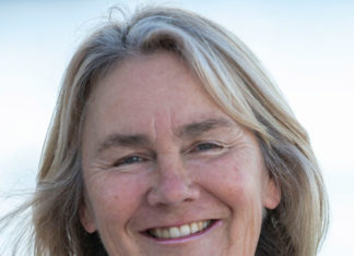 a woman with a pearl necklace smiling for the camera