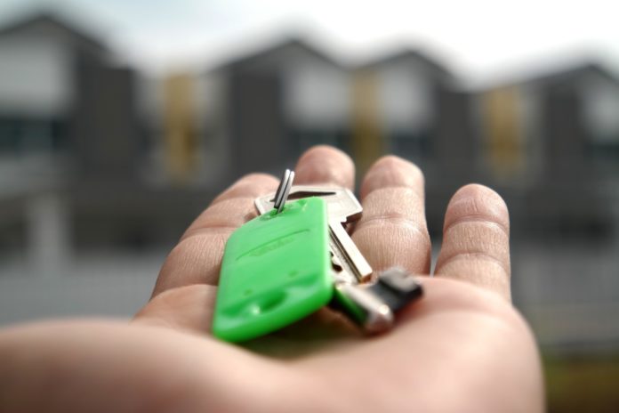 a hand holding a bunch of keys in front of a row of houses