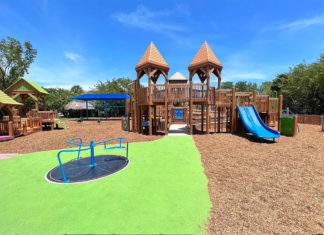a playground with a blue slide and green grass
