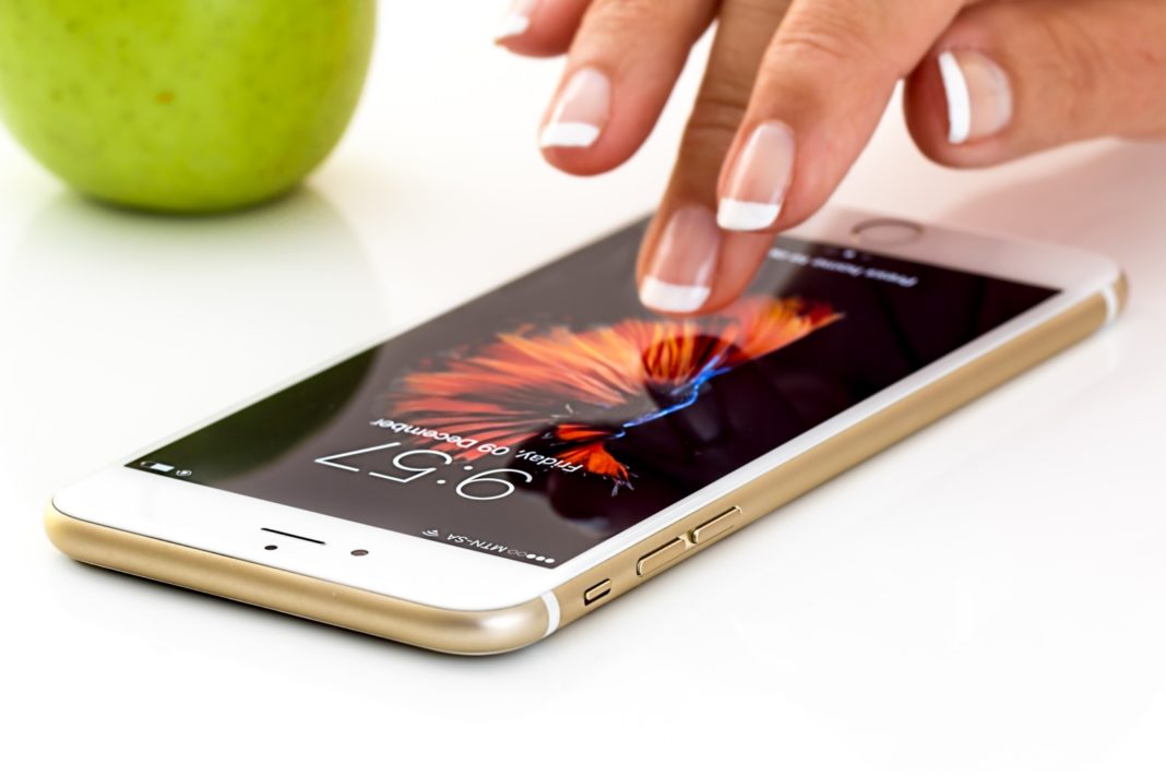 a woman touching the screen of a cell phone next to an apple